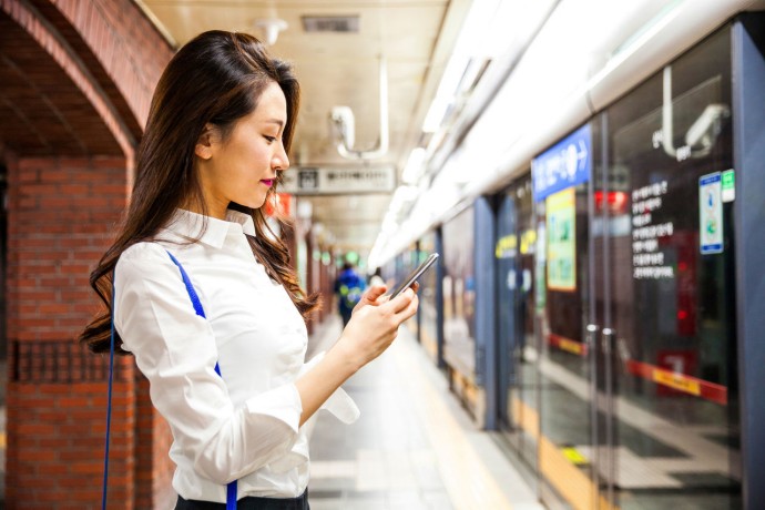 Business woman using a smart phone in the subway of South Korea